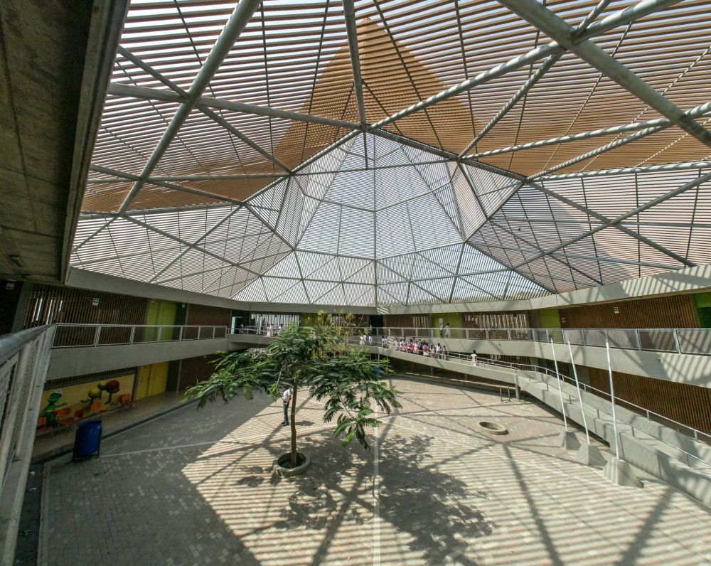 A lattice roof casting geometric shadows into a planted courtyard