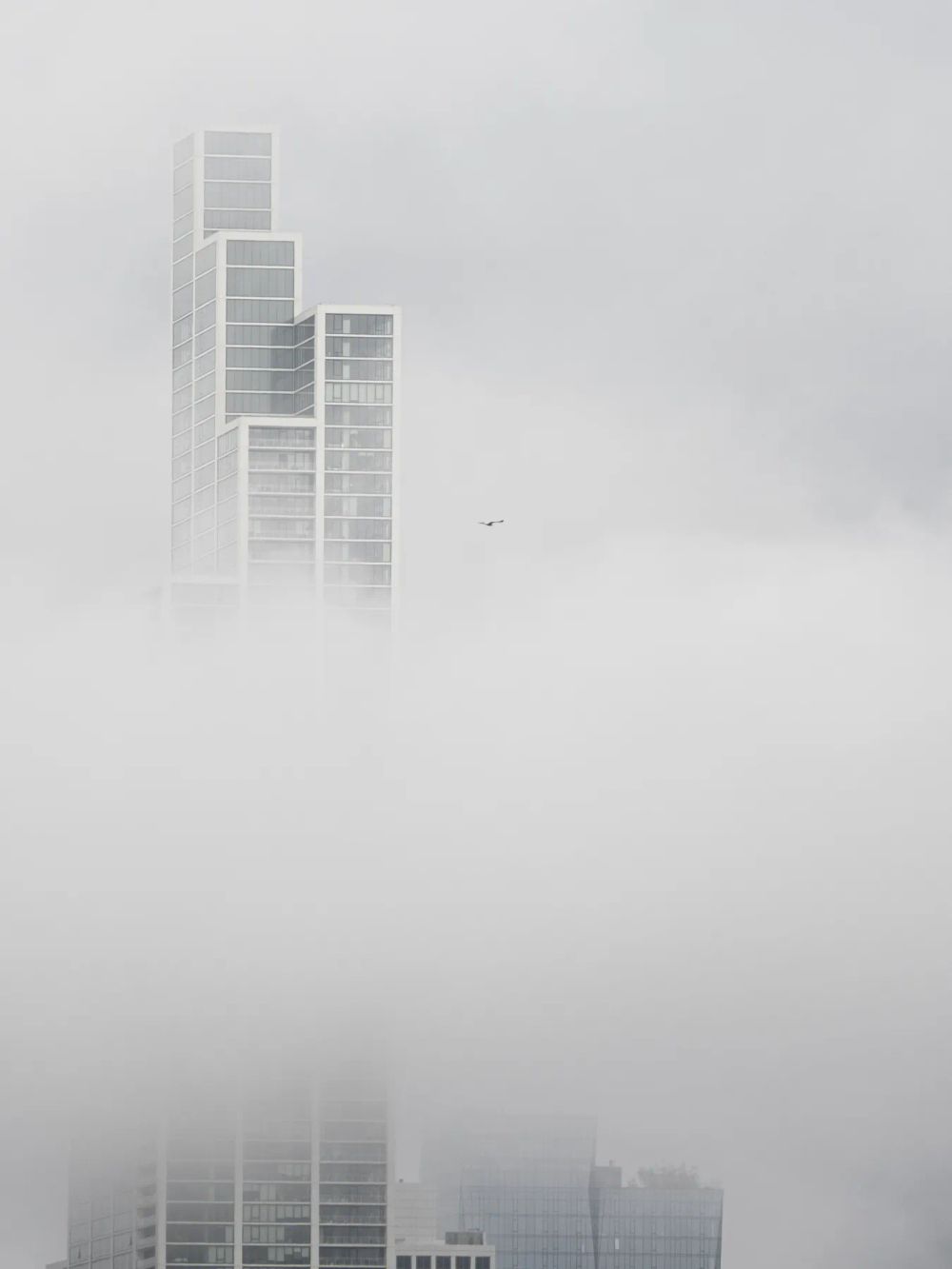 The upper floors of a stepped tower fading into pale fog