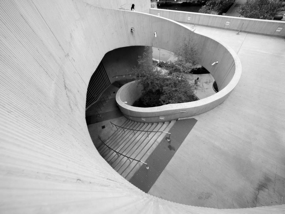 A spiral concrete courtyard and stair seen from above in black and white