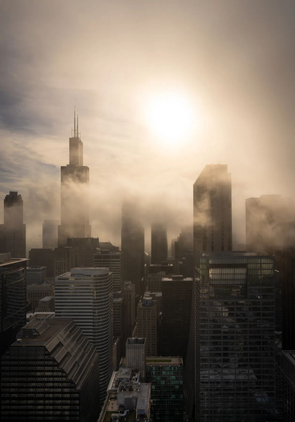 Sunlight breaking through fog around a cluster of city towers