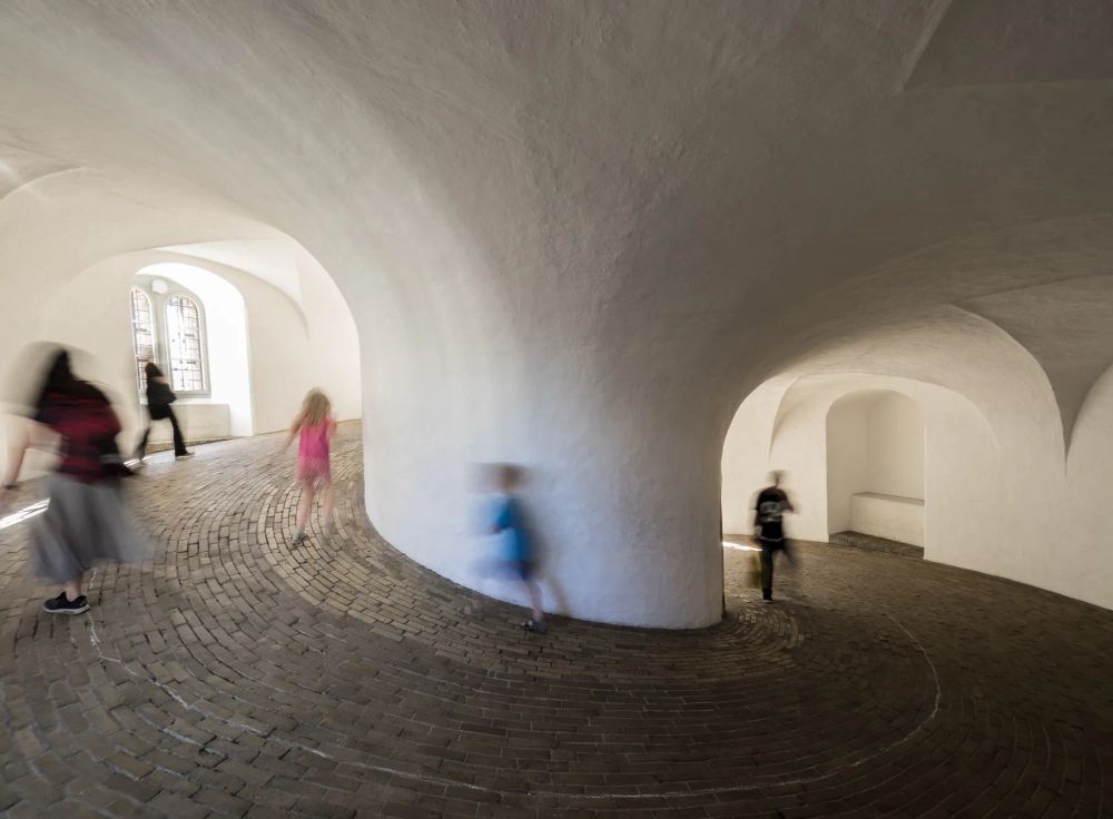 Blurred visitors moving through white vaulted passages