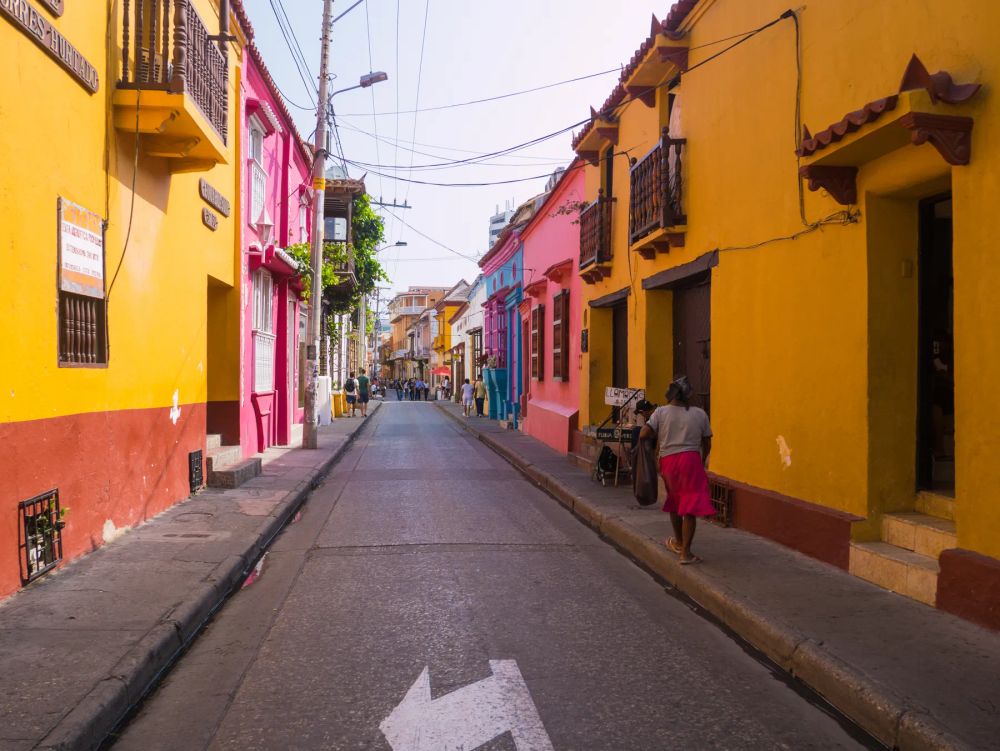 A pedestrian on a narrow street lined with colorful facades