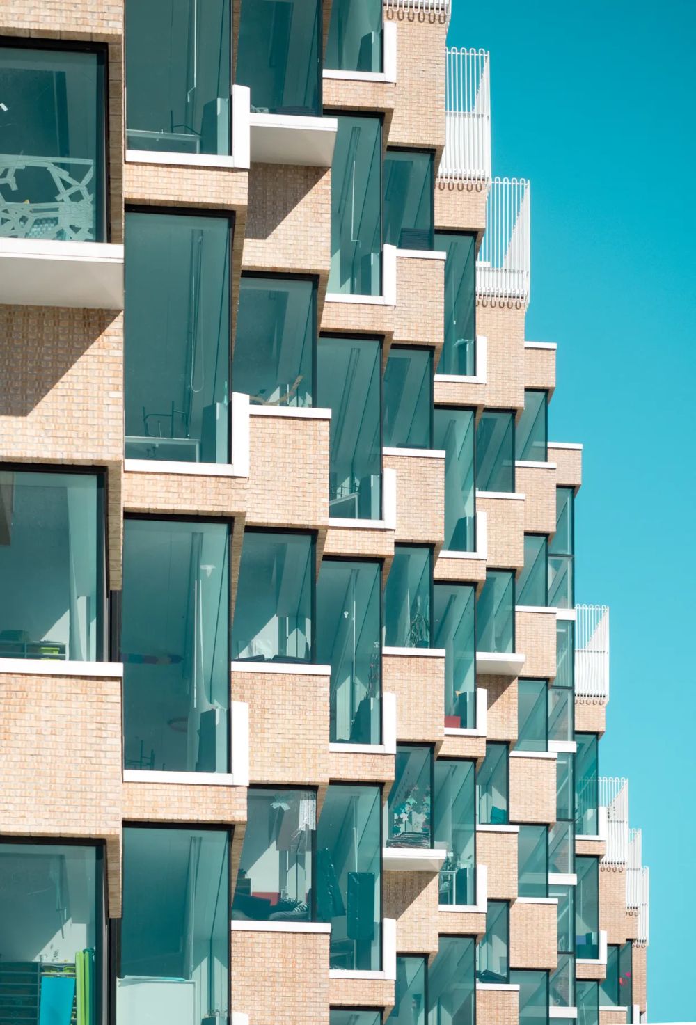 White stepped balconies projecting from a turquoise glass facade