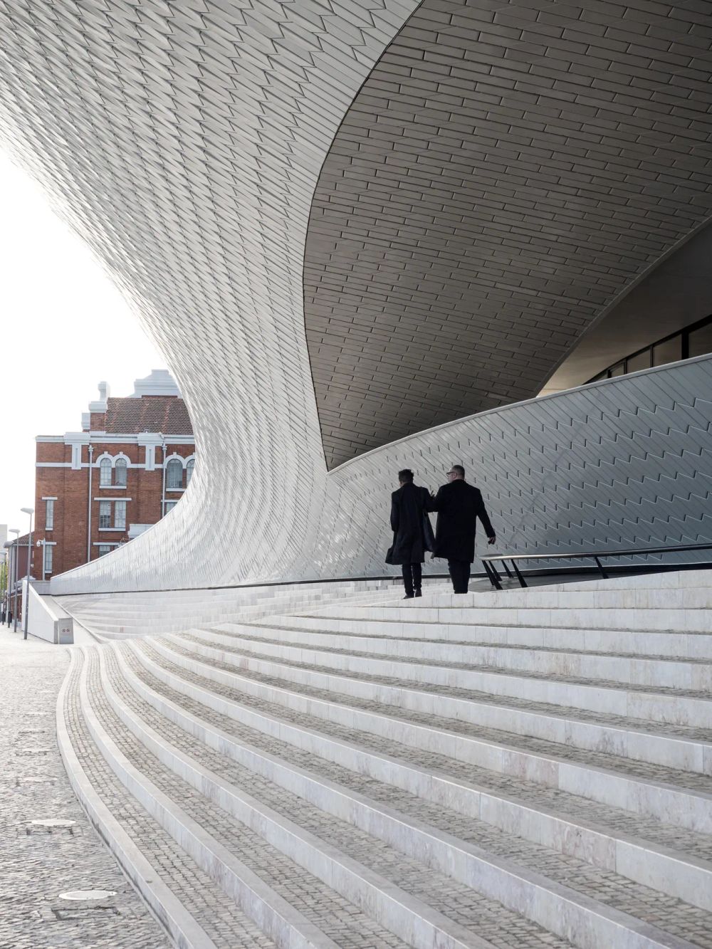 Two people beneath a sweeping shell above curved steps