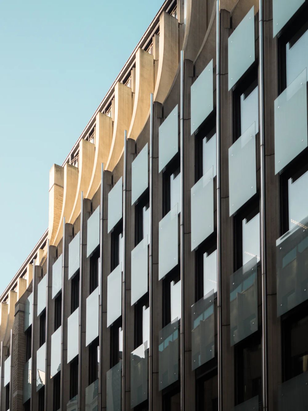Angled metal facade panels casting deep shadows beside dark windows