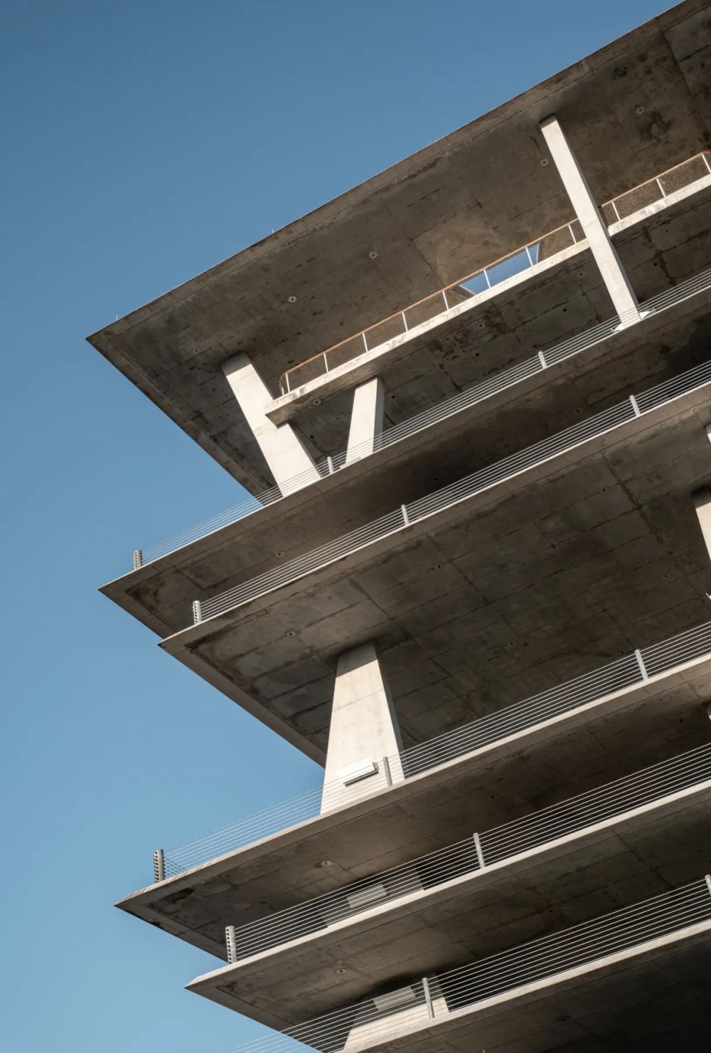 Exposed concrete floor slabs and slender columns against a blue sky
