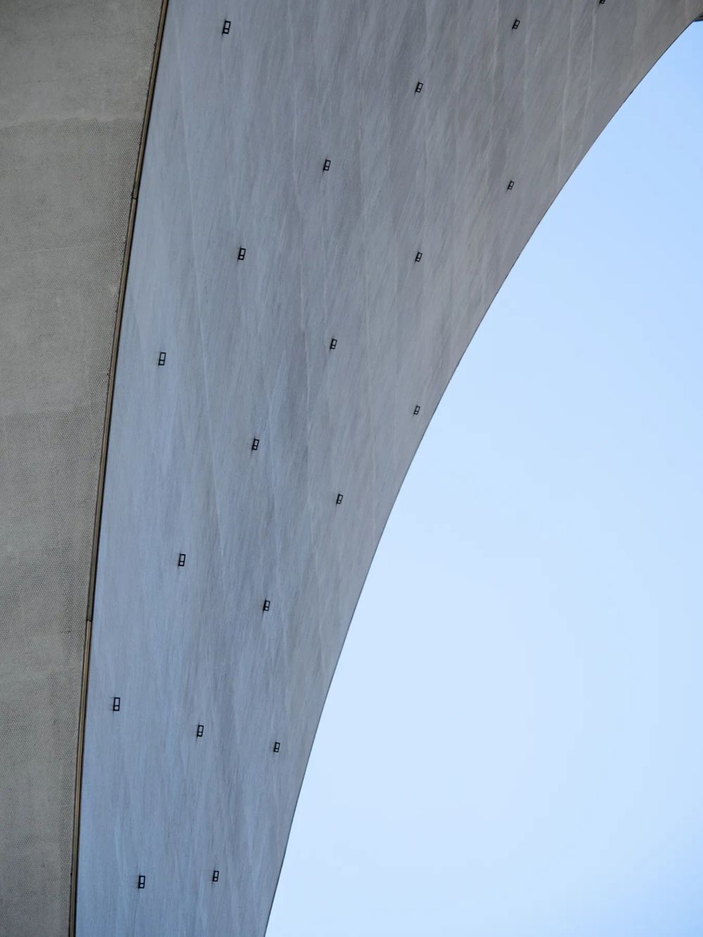 A curved concrete surface framing a narrow opening of blue sky
