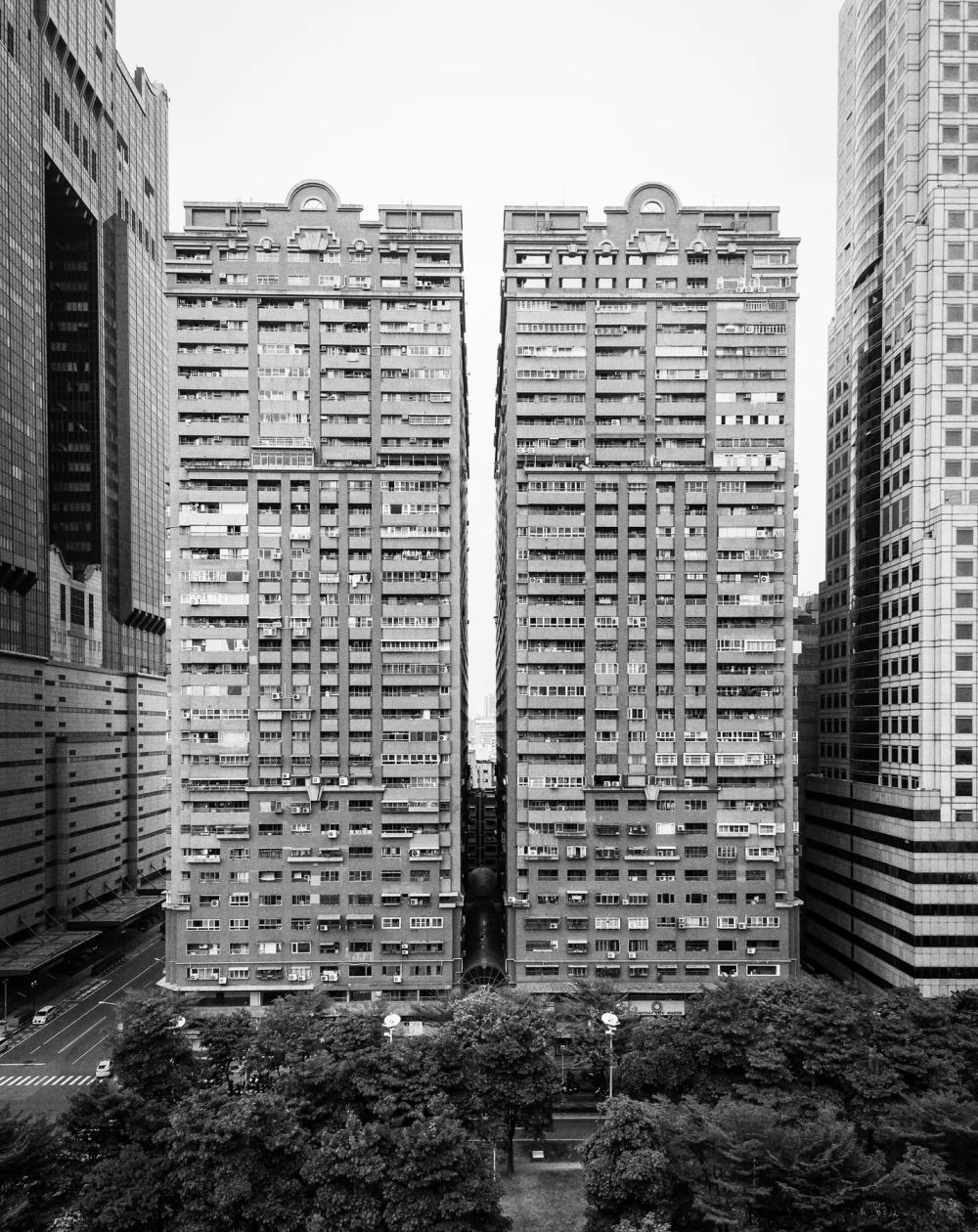 Dense residential towers framed by neighboring buildings in black and white