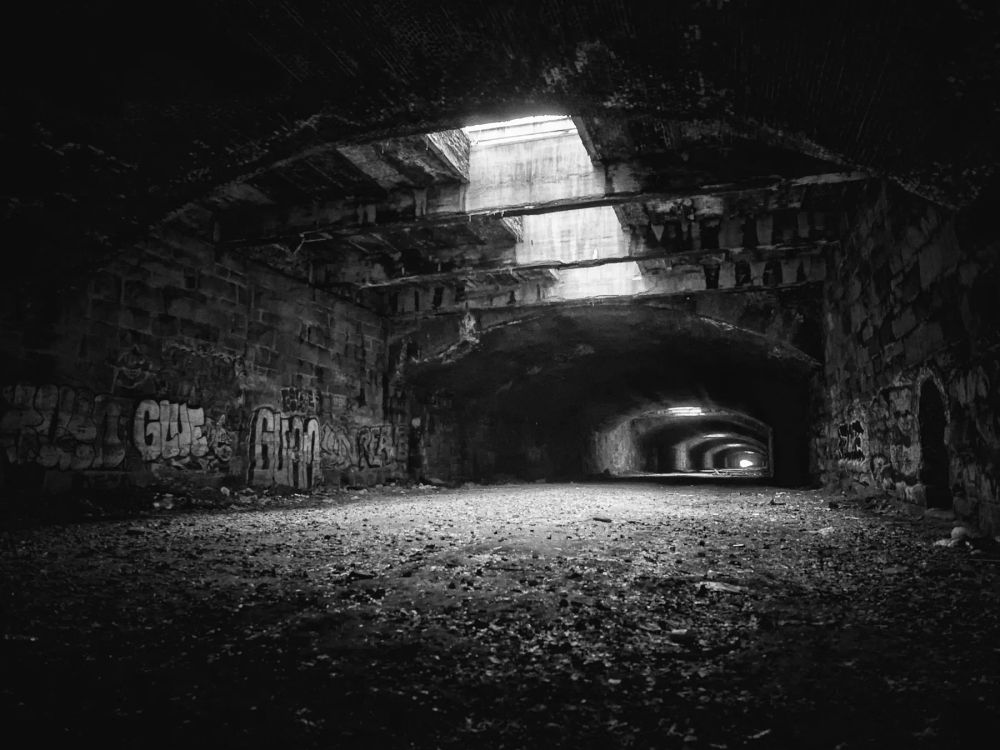 Daylight entering a dark weathered stone passage through roof openings