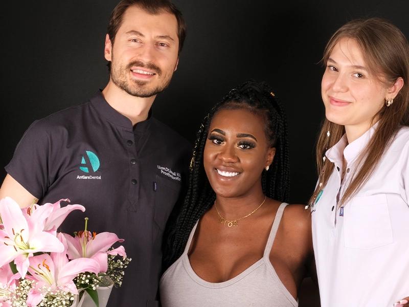 Patient posing with two clinicians holding flowers