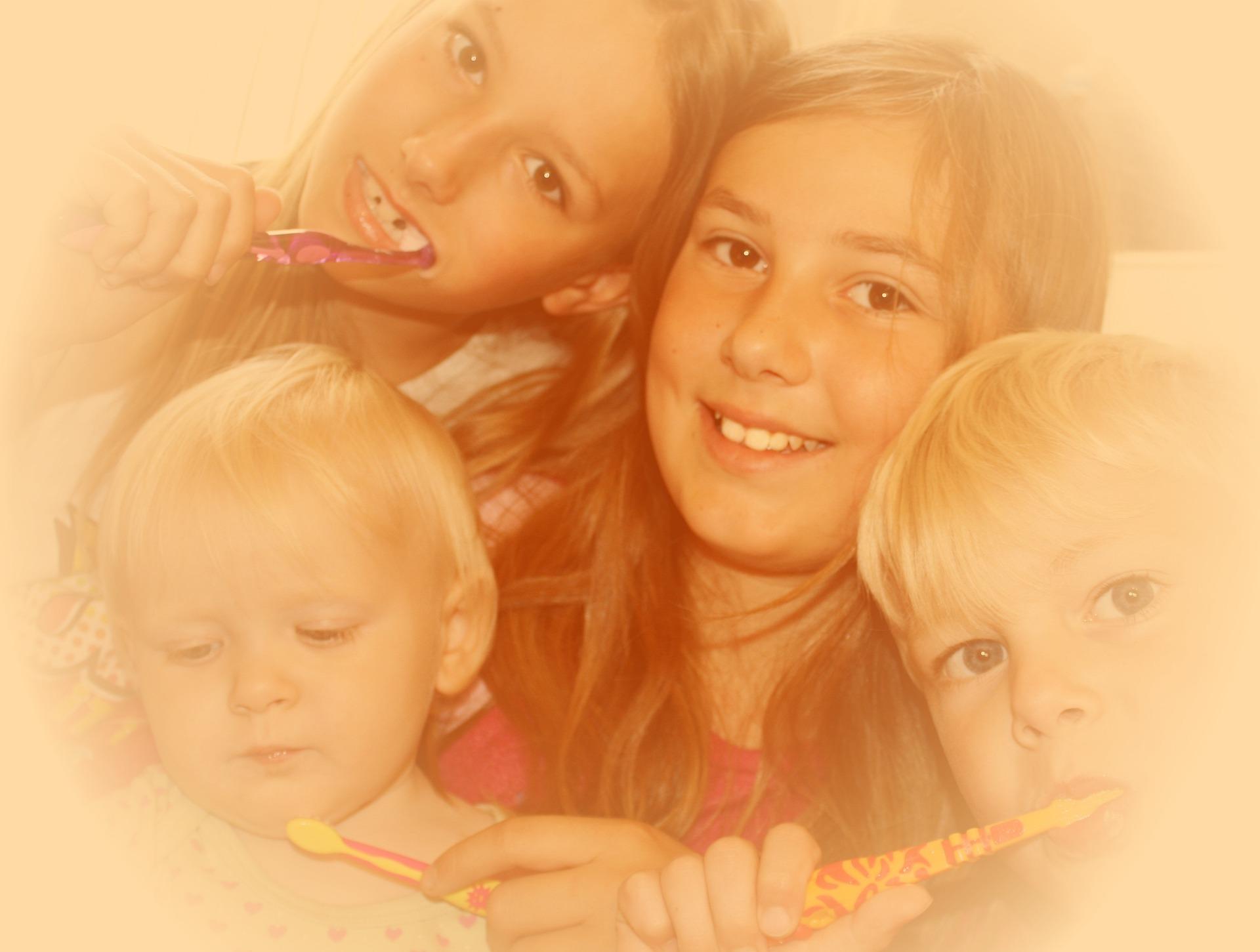 Three children holding toothbrushes, two brushing