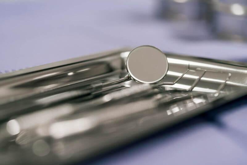 Mirror and hand instruments used for dental examination and cleaning, on a tray