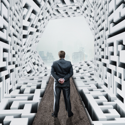 Man in a suit standing in a maze corridor seen from behind
