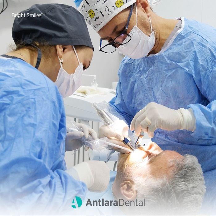 Two clinicians in gowns performing a procedure on a patient
