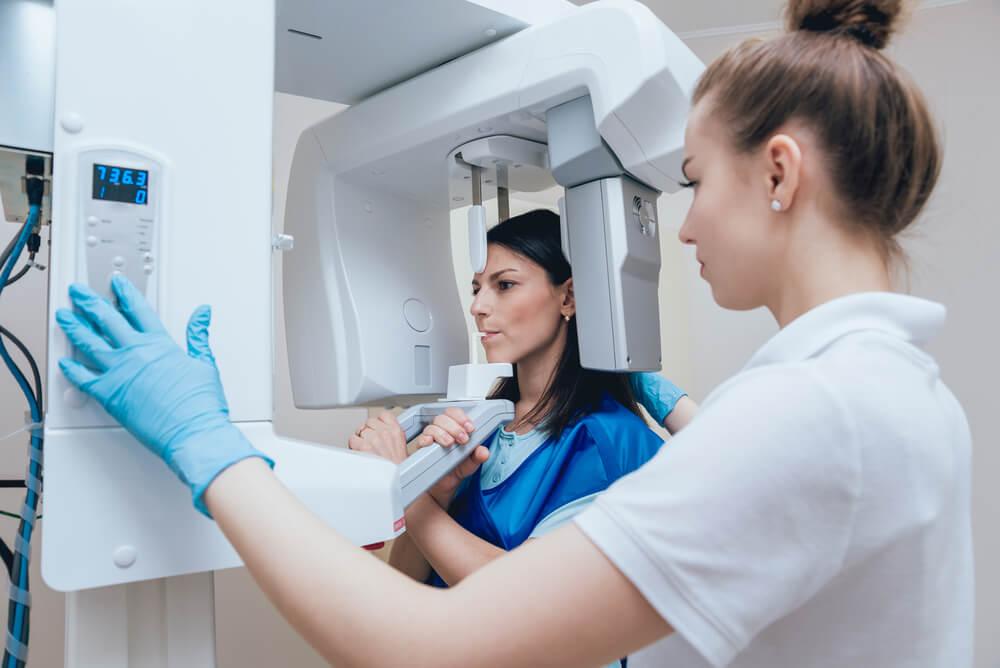 Patient in a dental x-ray scanner operated by a staff member