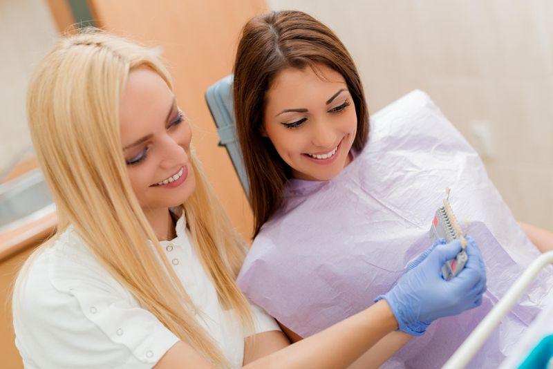 Two women looking at a tooth shade guide