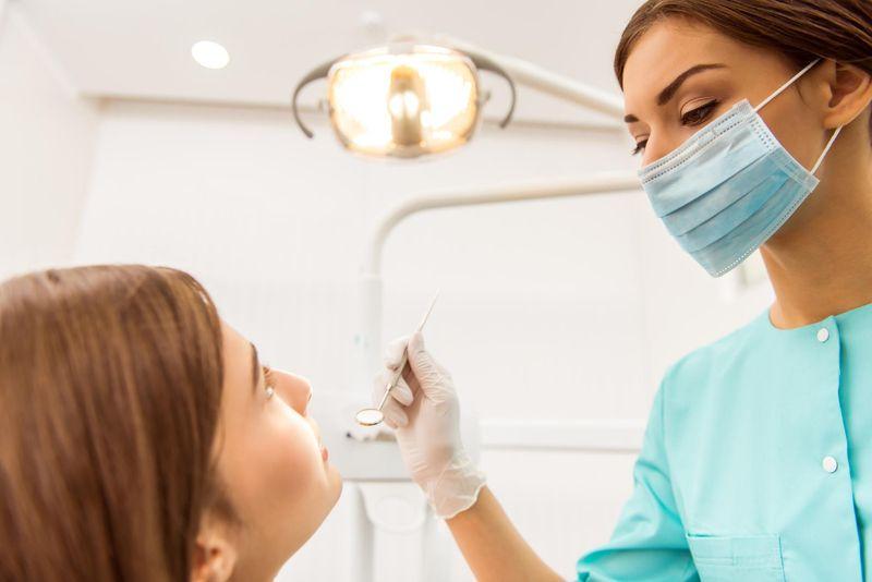 Dentist with a mouth mirror examining a patient