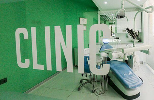 Treatment room with a dental chair behind green glass lettering