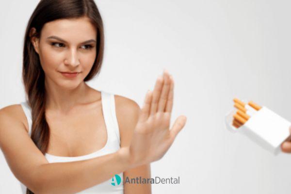 Woman holding up a hand to refuse a pack of cigarettes