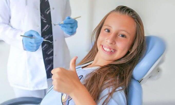 Girl giving a thumbs up in a dental chair