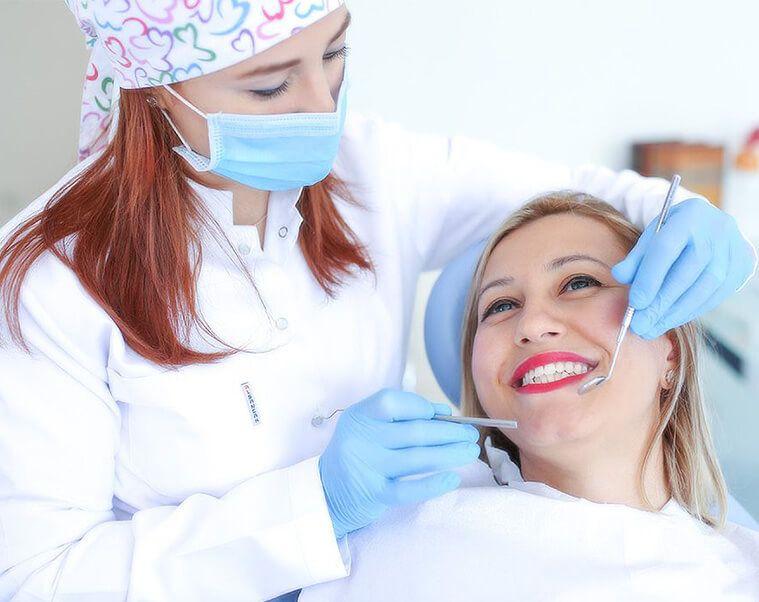 Dentist examining a smiling patient with a mirror and probe