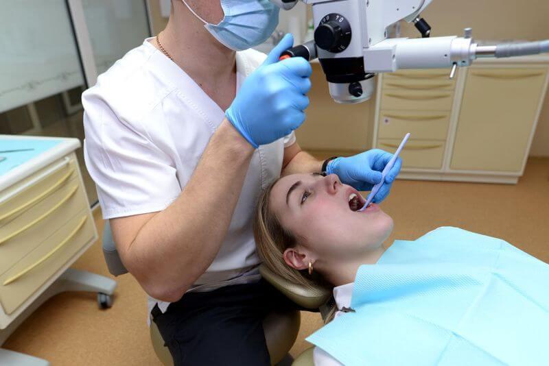 Dentist examining a patient with a dental microscope