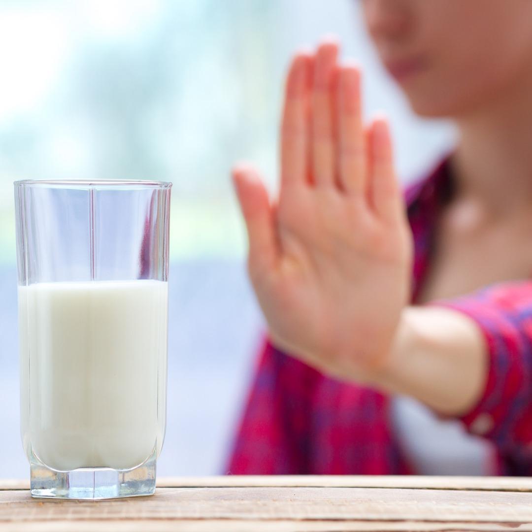 Glass of milk with a hand raised to refuse it