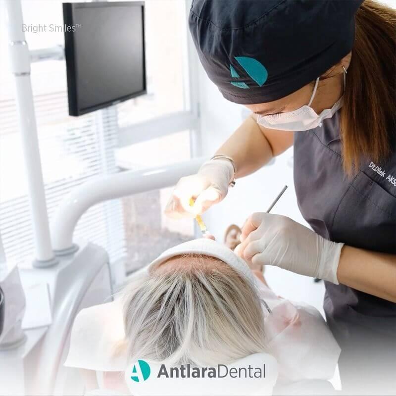 Dentist in a surgical cap and mask treating a reclined patient