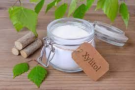 Jar of xylitol with a label and small wooden sticks