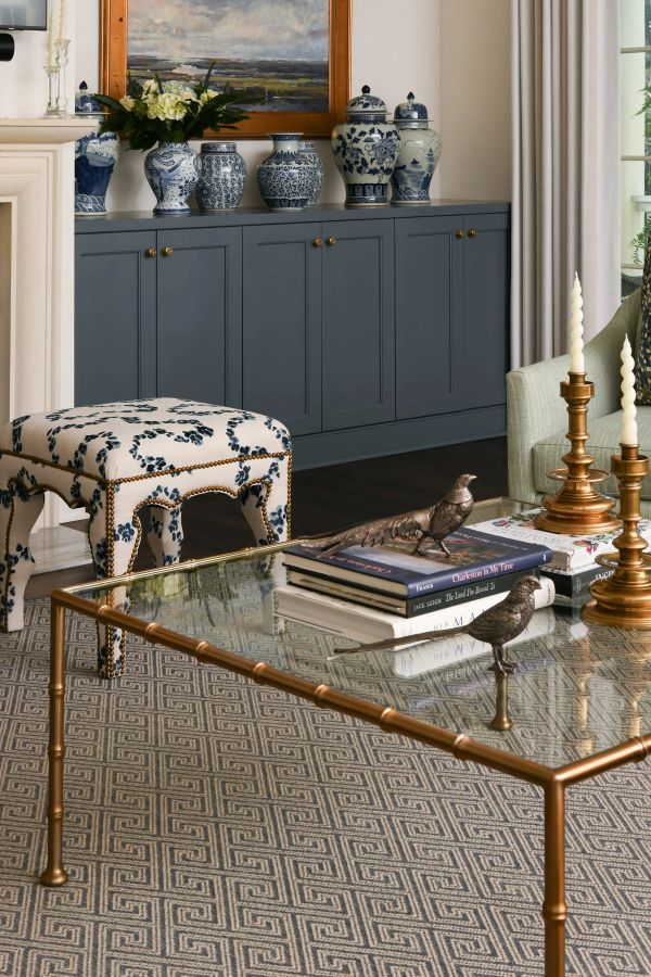 Living room detail with a brass bamboo-style coffee table, blue and white floral stool, and dark gray built-in cabinets styled with chinoiserie vases and hydrangeas