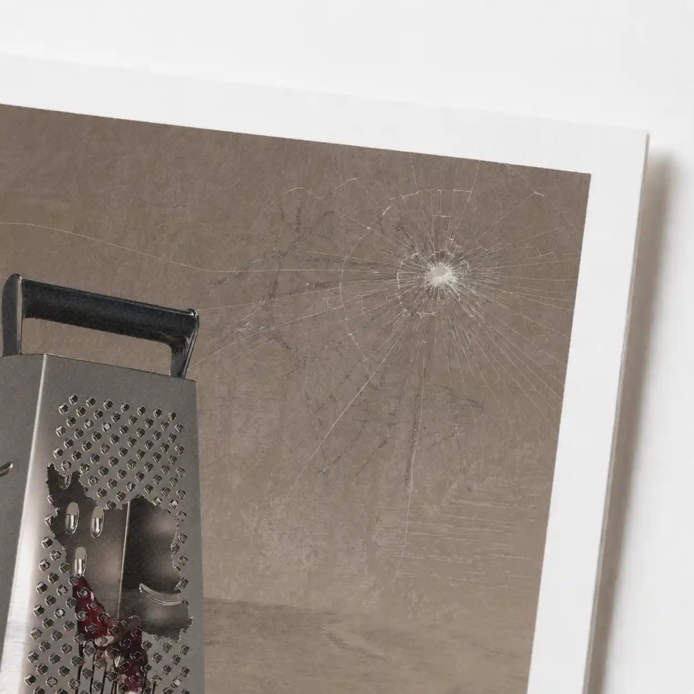 3D digital art of a metal grater with a bleeding Iran-shaped cutout and a bullet impact on a gray wall.