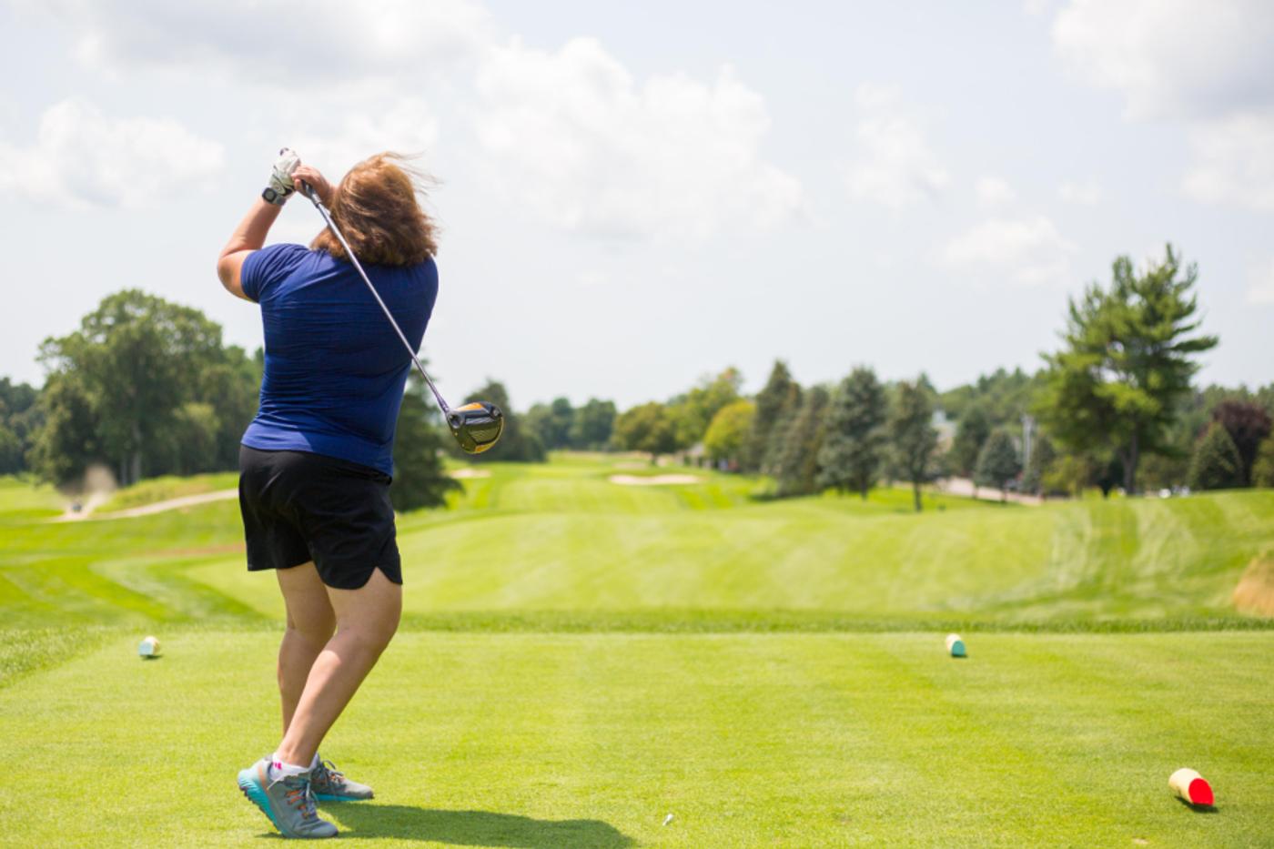 A golfer following through on a tee shot down an open fairway