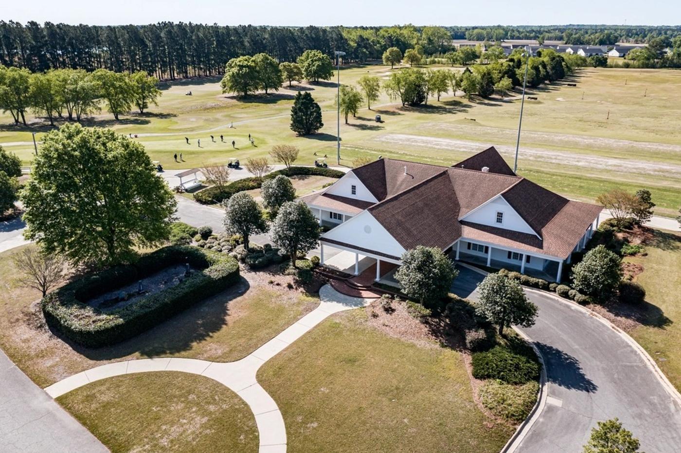 An aerial view of a golf course clubhouse and green with players finishing a round