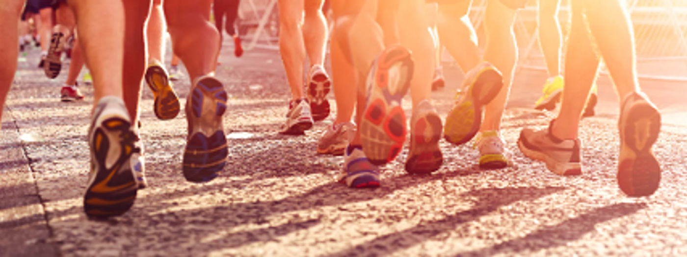 Close-up of runners’ feet on a road in warm low sunlight