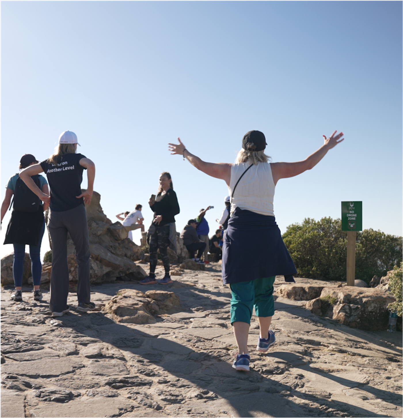 Participants celebrating with arms raised at the top of a mountain trail
