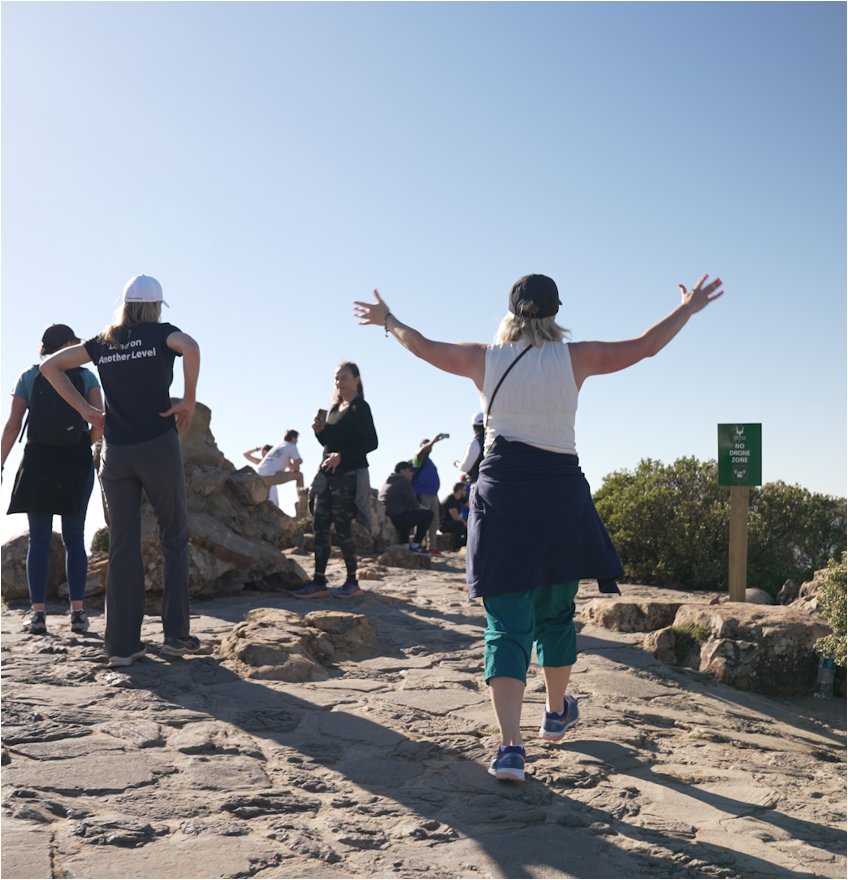 Participants celebrating with arms raised at the top of a mountain trail