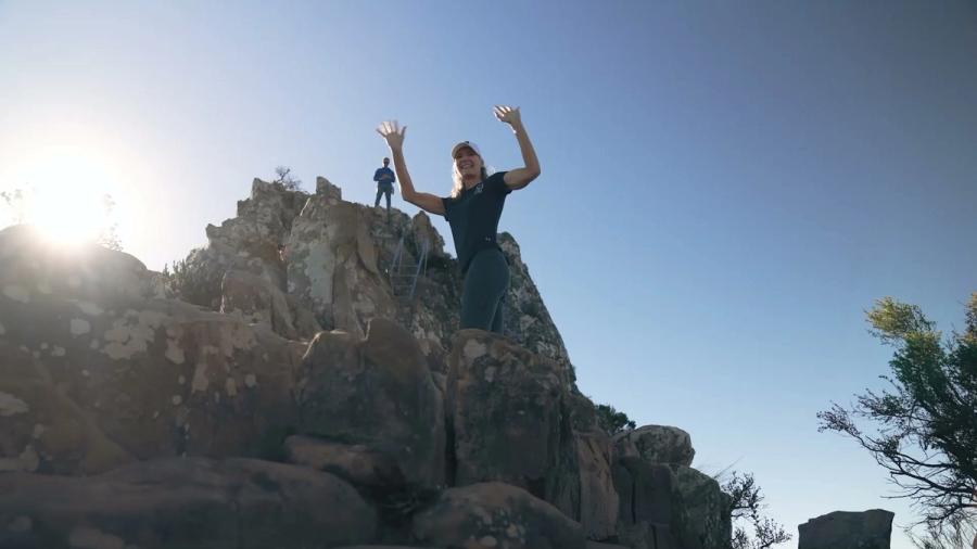 A participant celebrating on a rocky summit