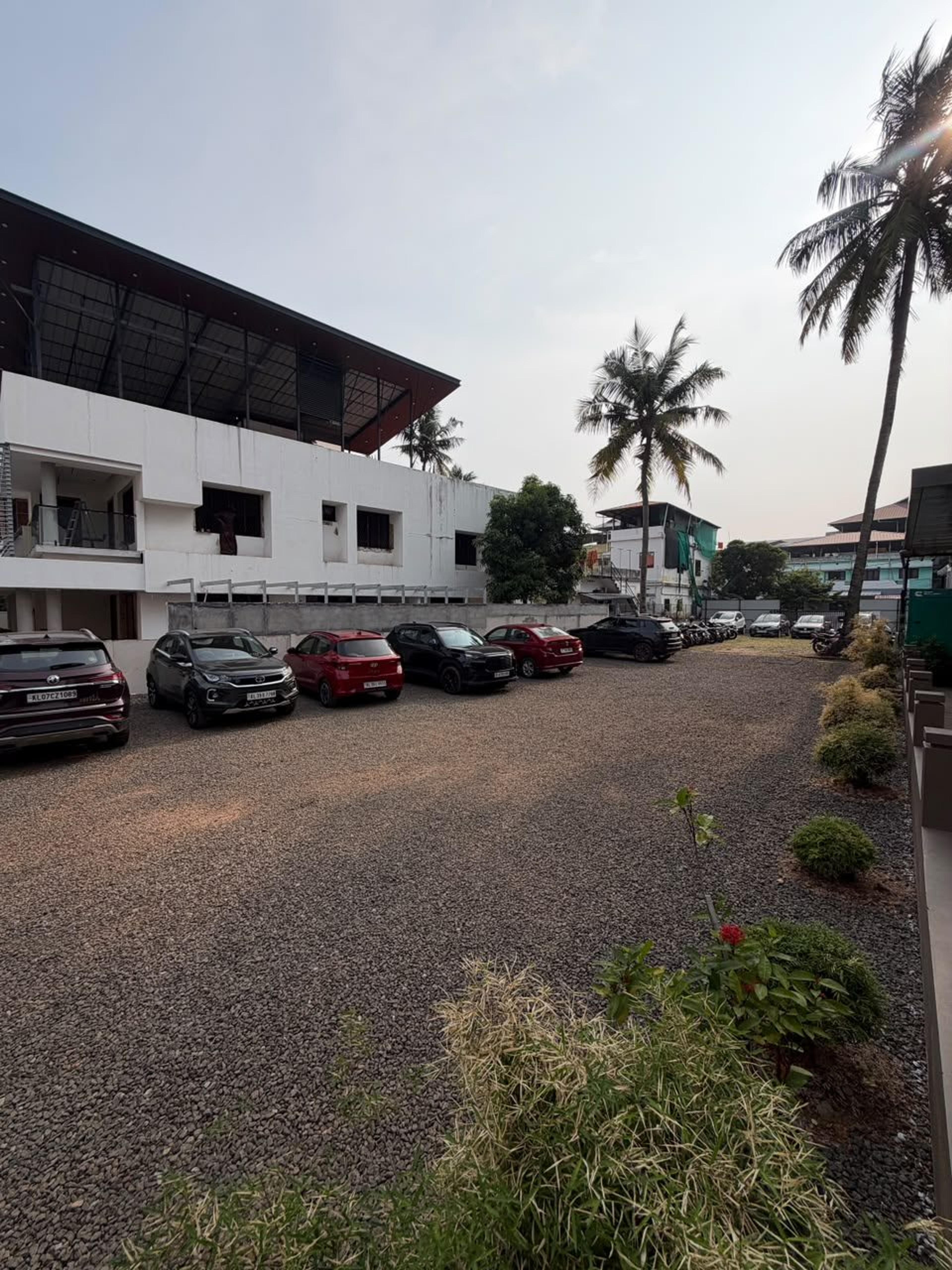 Wide view of the gravel car park with cars and two-wheelers