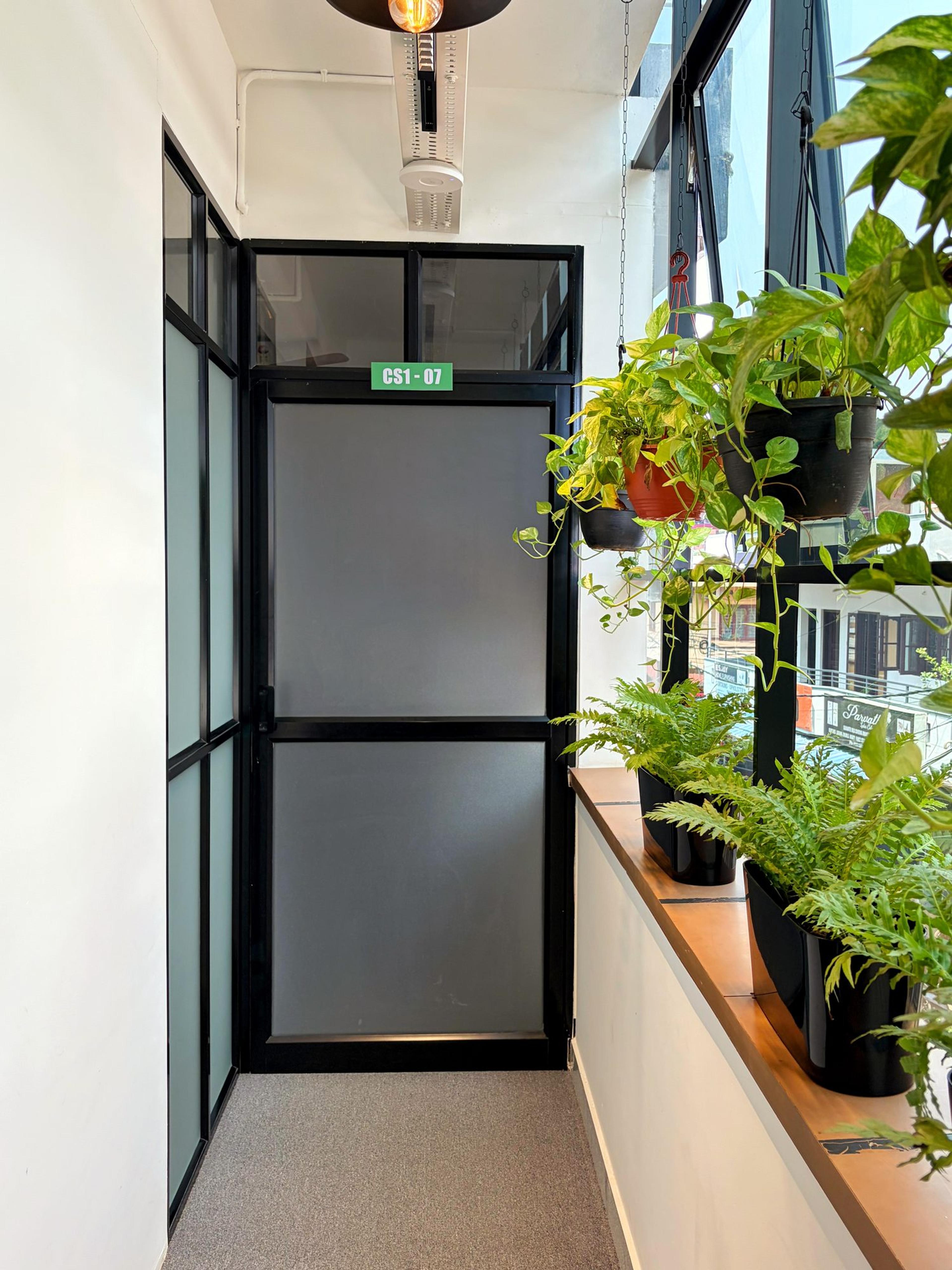 Glass-panelled door to cabin CS1-07 beside hanging pothos and fern planters