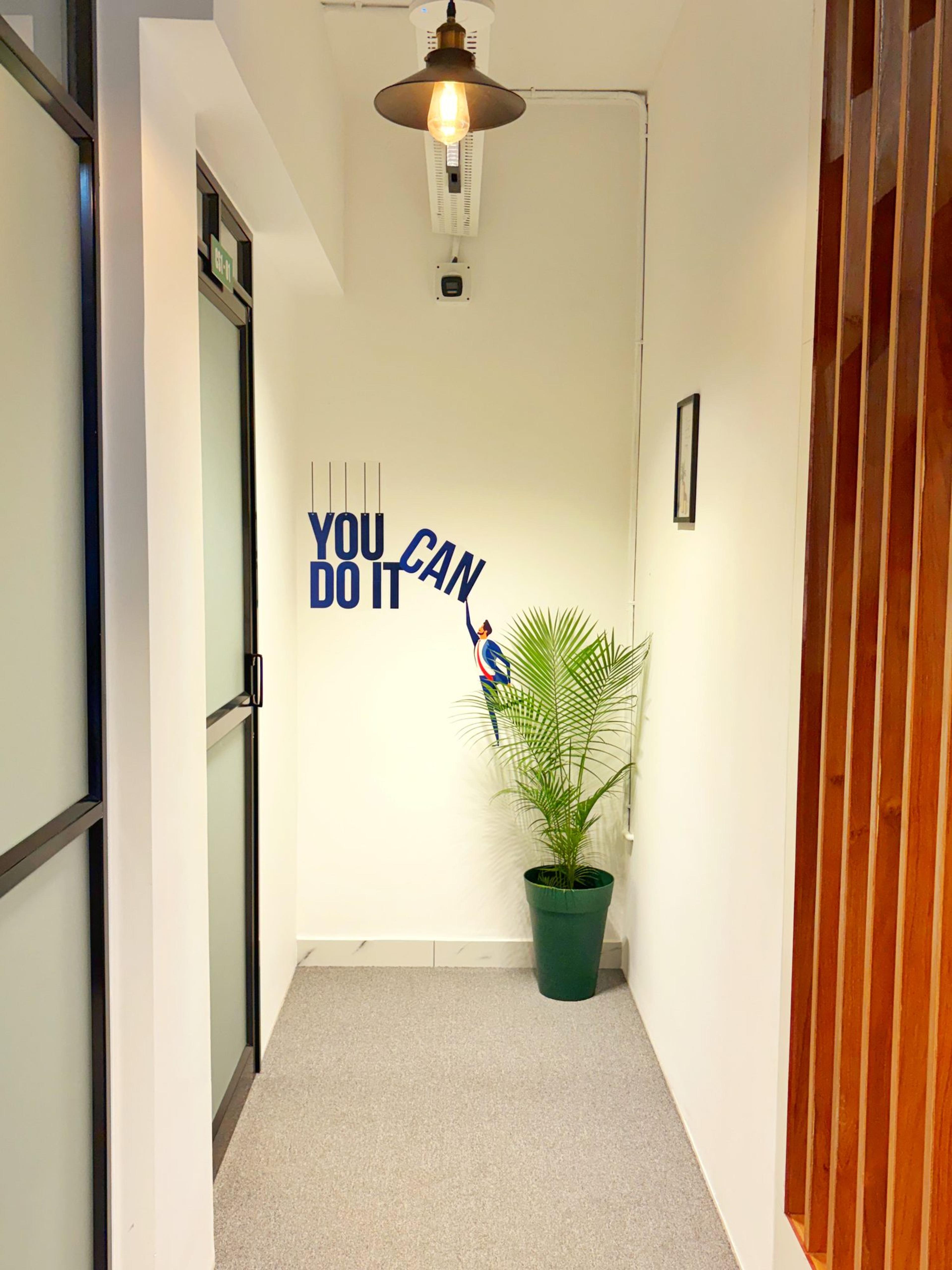 Corridor corner with a “You can do it” wall graphic, a pendant lamp and a potted palm