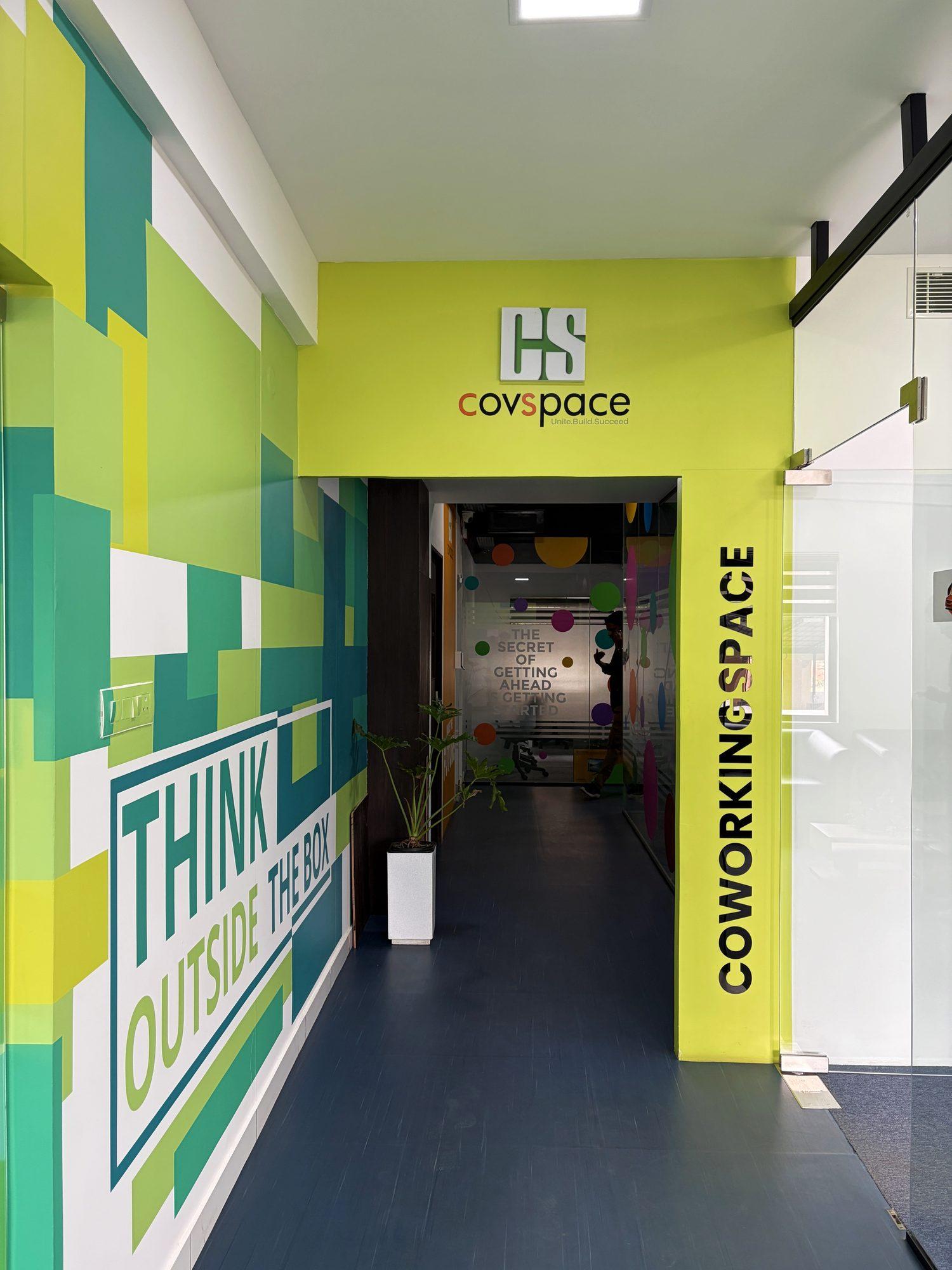 Lime-green coworking entrance with the Covspace logo and a “Think outside the box” wall