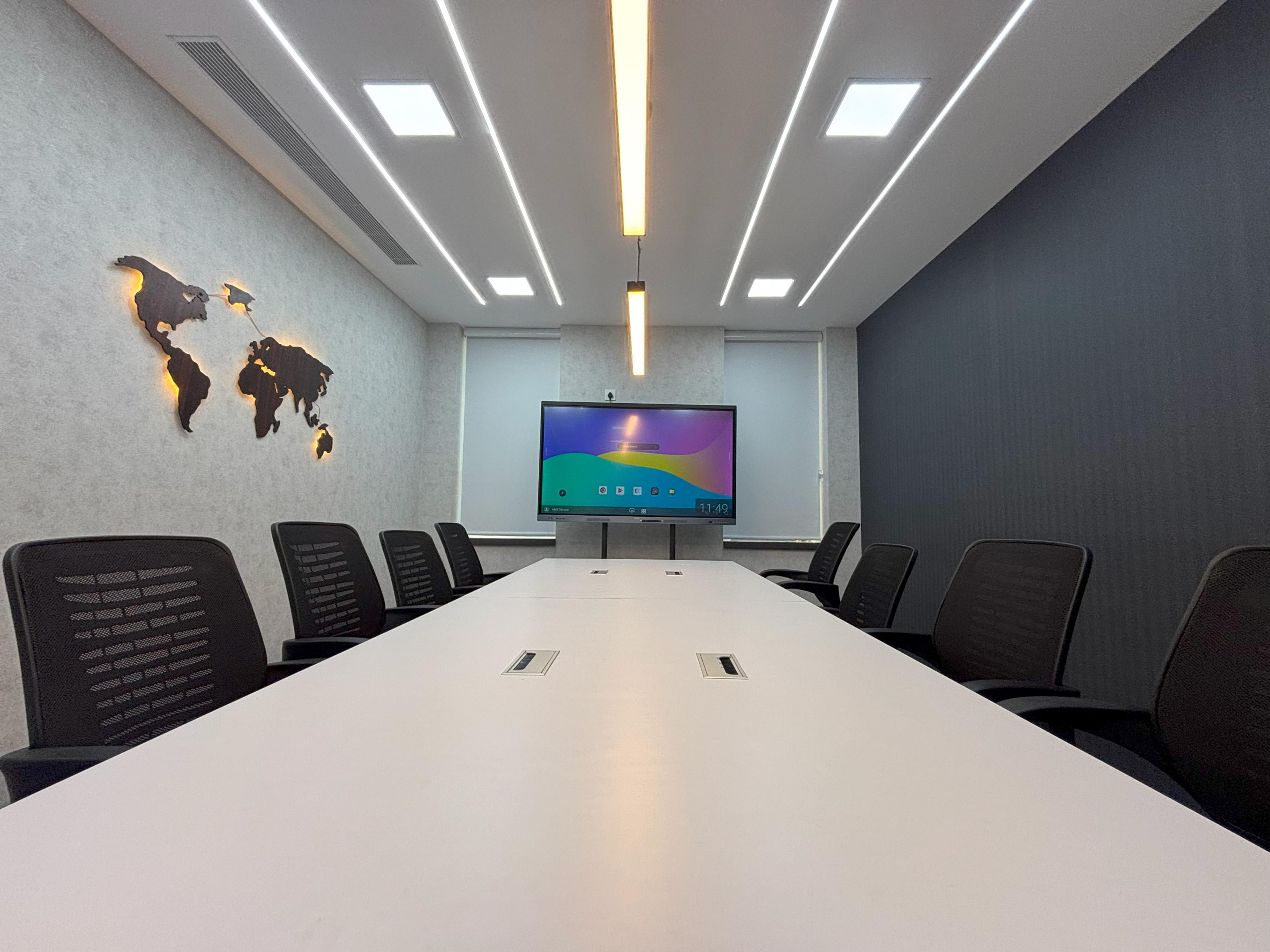 Covspace meeting room with a long white table, interactive display and illuminated world map wall