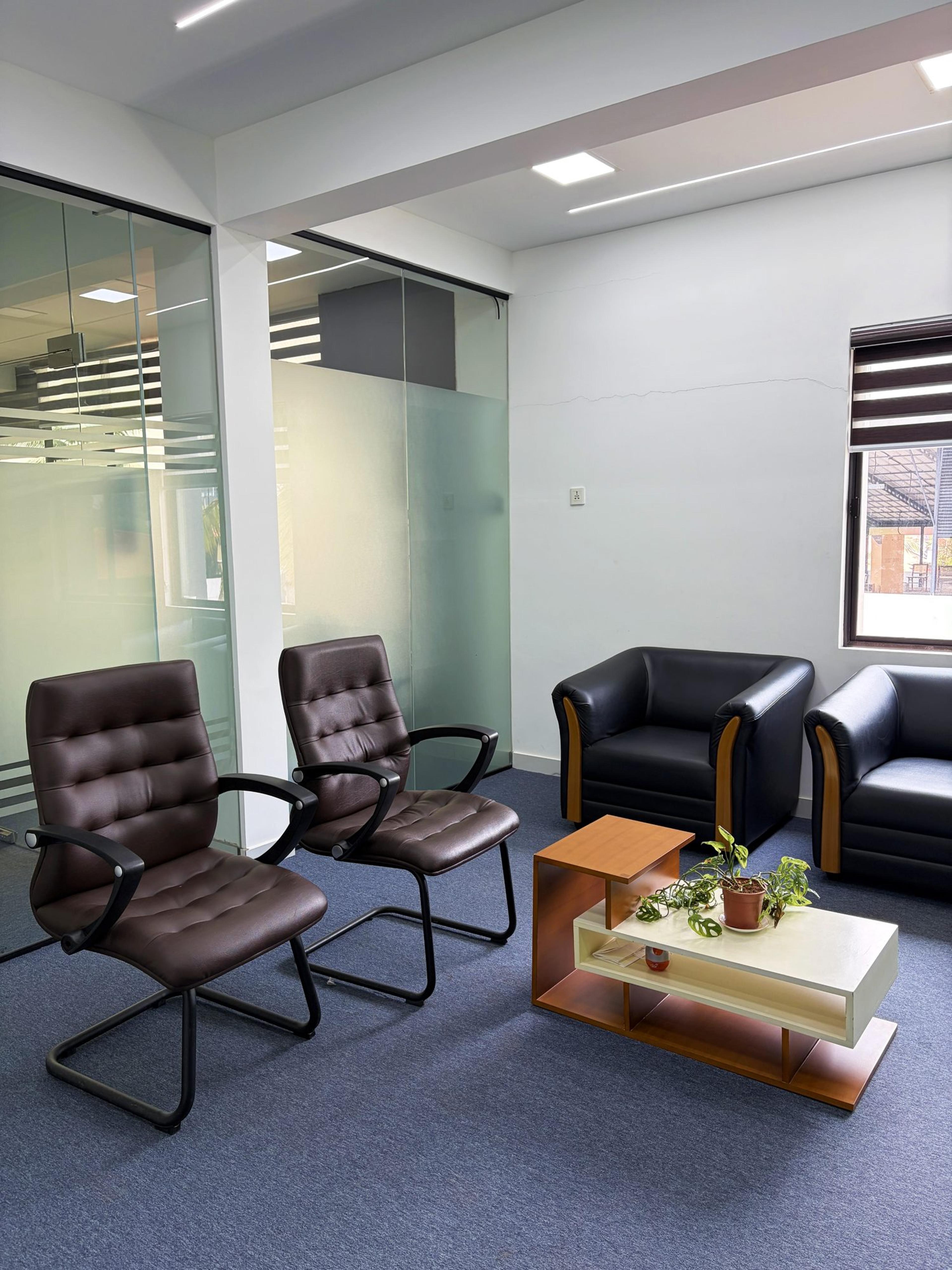 Visitor lounge with leather chairs, black sofas and a coffee table beside glass partitions