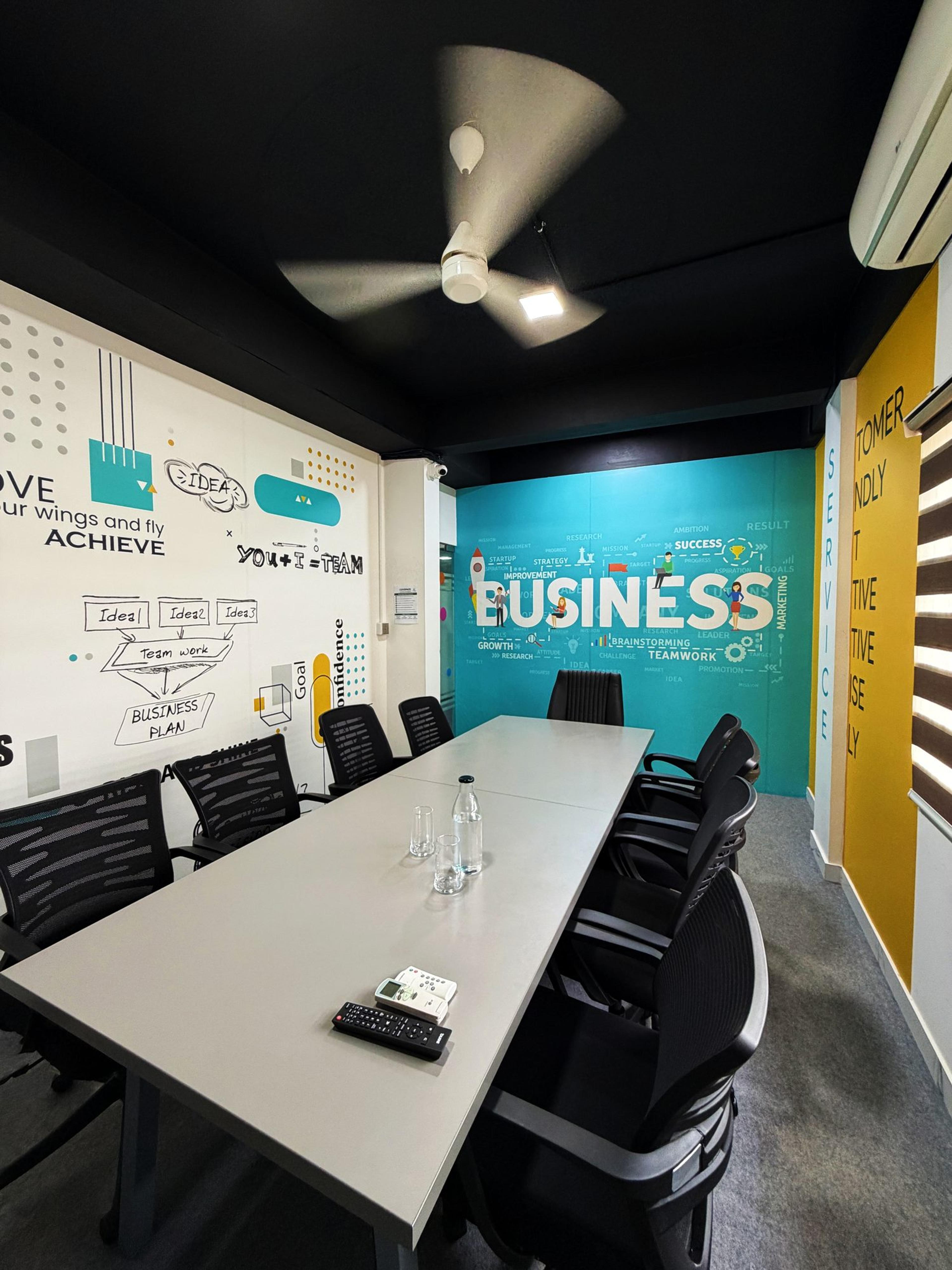 Covspace meeting room with a long table, mesh chairs and a teal “Business” mural