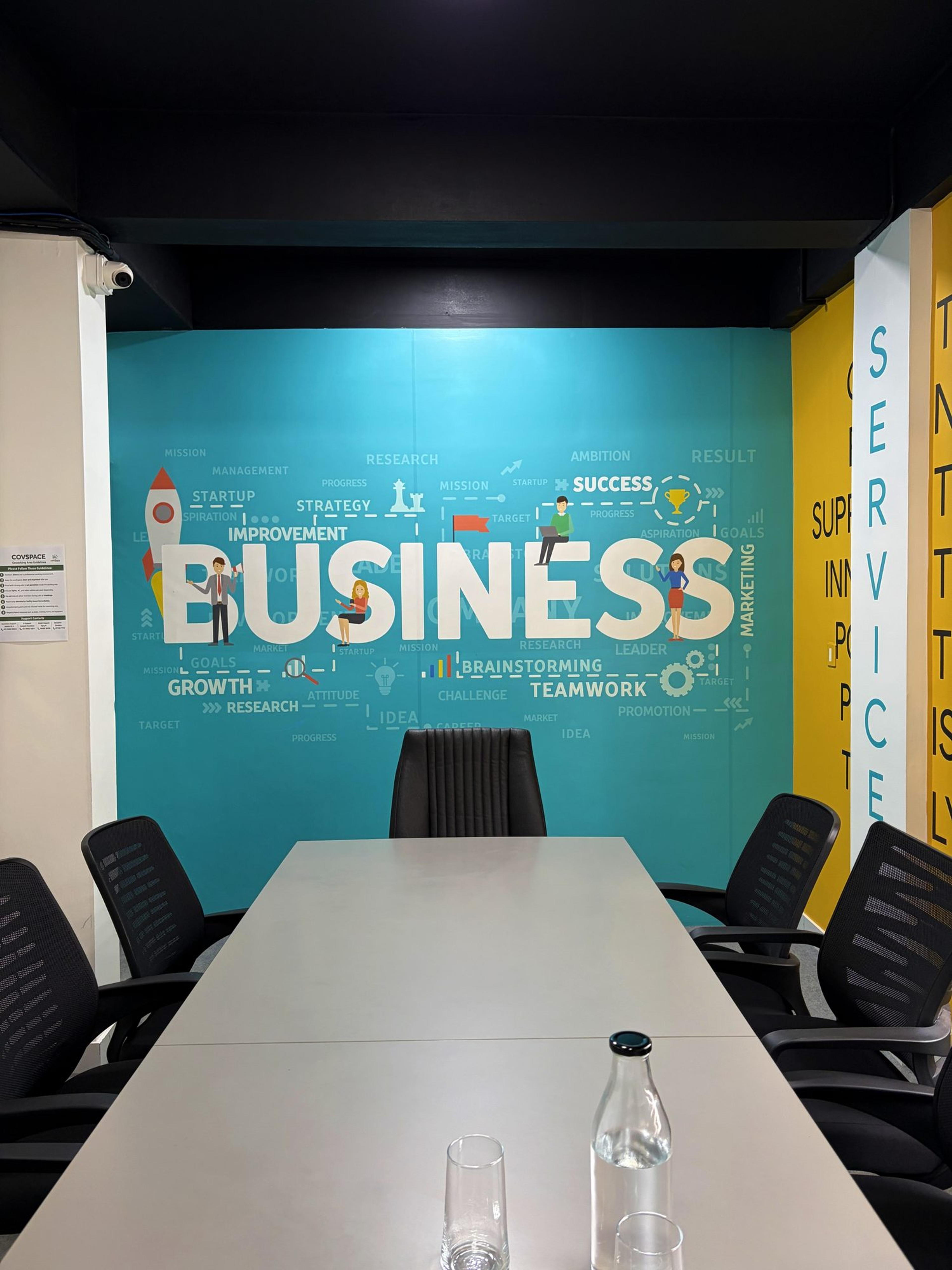 Head of the meeting room table facing the teal “Business” wall graphic