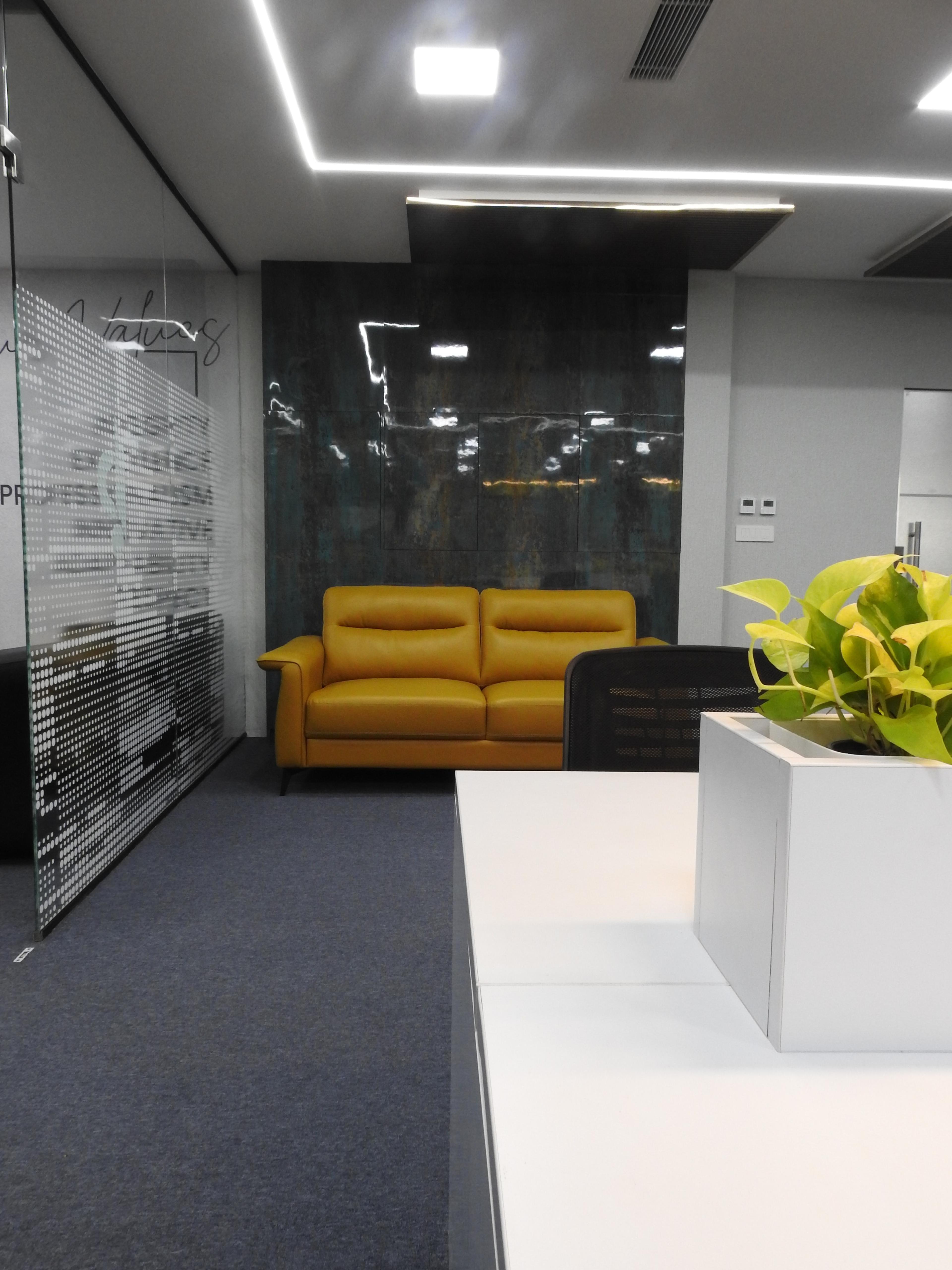 Flexi desk with a planter, a mustard sofa and glass partitions beyond