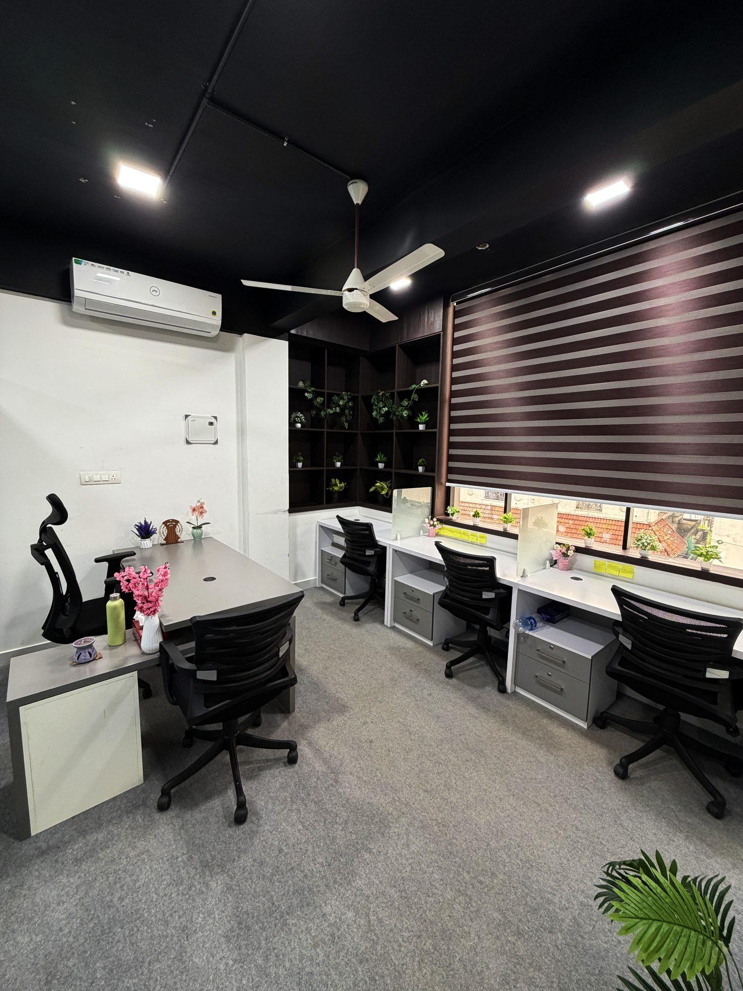 Premium private cabin with a manager desk, three workstations, shelving with plants and a zebra blind