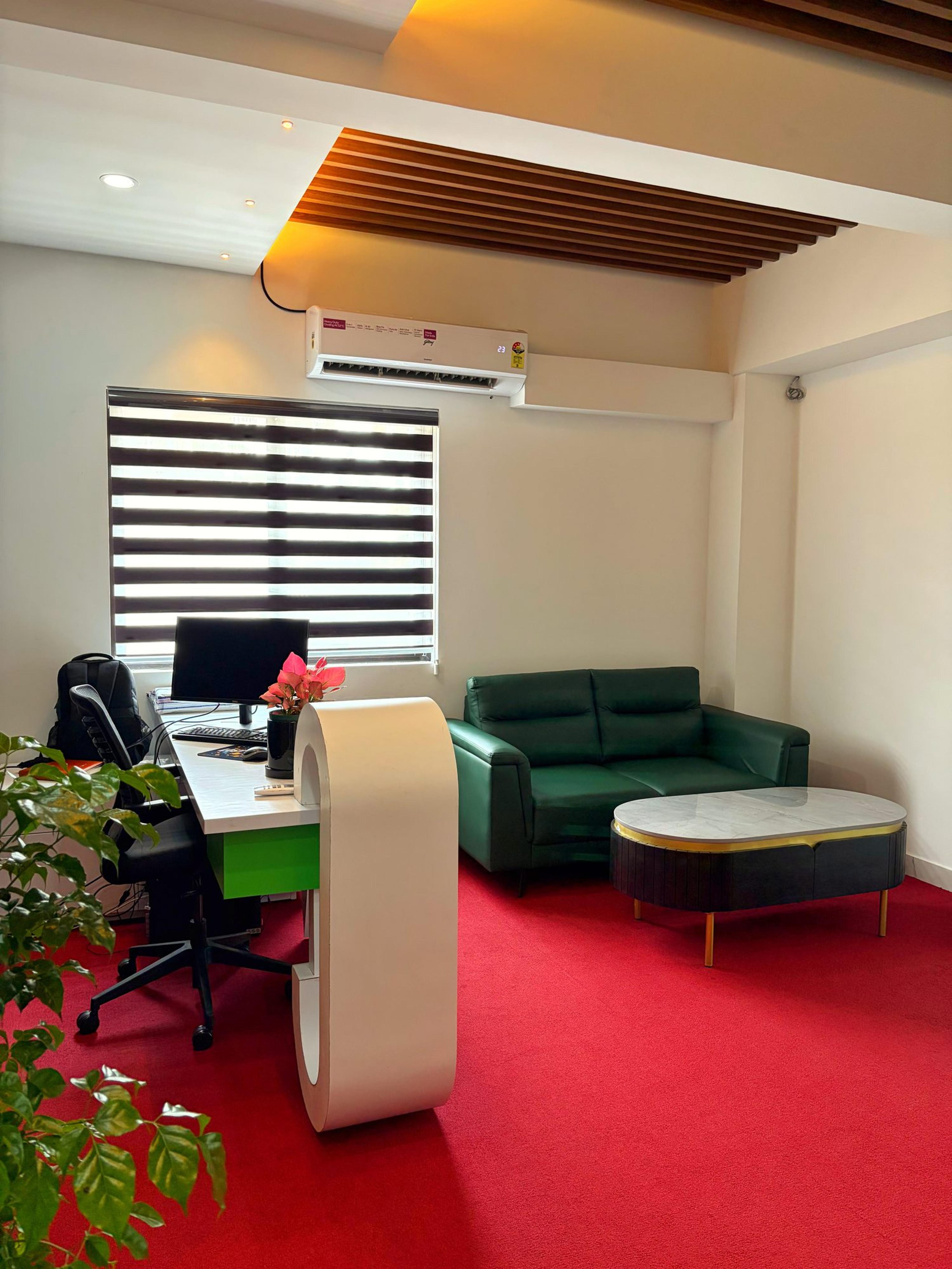 Reception desk with a curved white counter, green sofa and red carpet