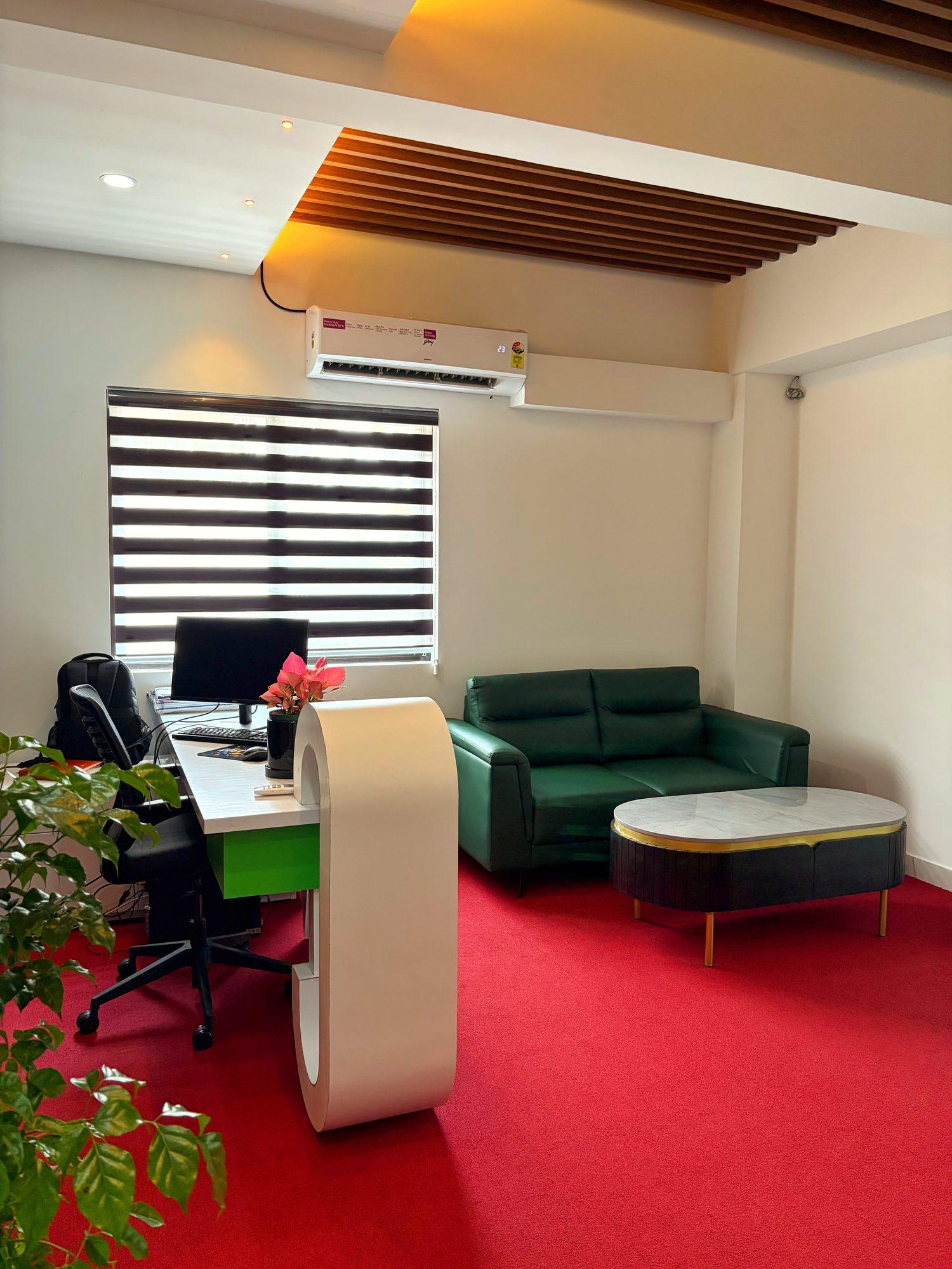 Reception desk with a curved white counter, green sofa and red carpet