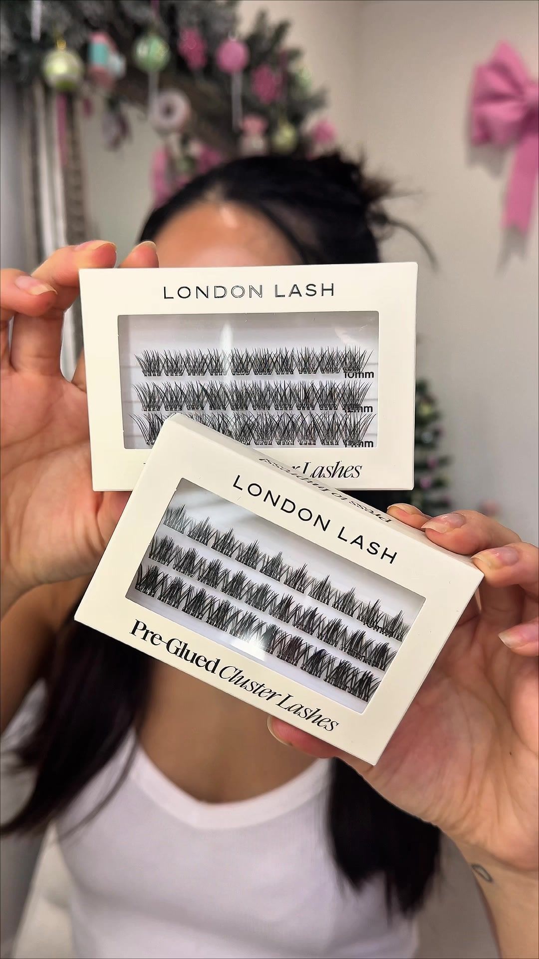A creator holds up two packs of London Lash pre-glued cluster lashes.